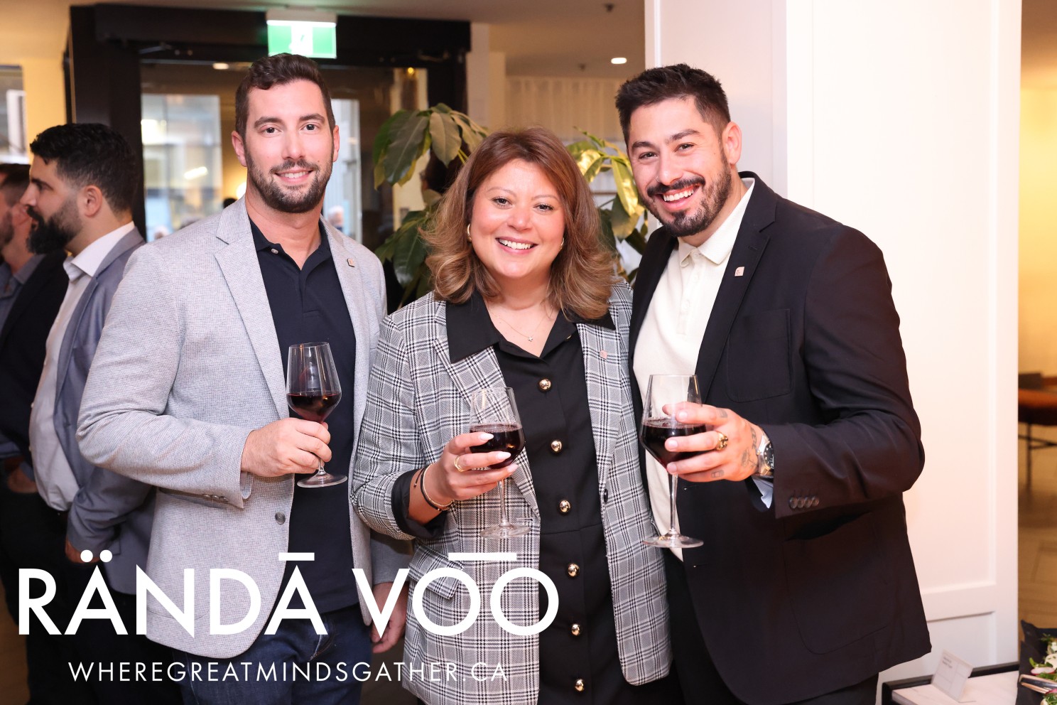 Three guests holding wine glasses at the gathering.