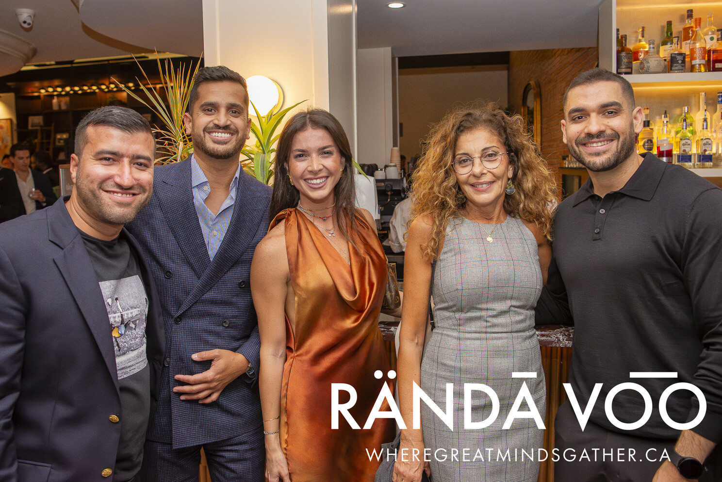 Five guests posing together beside the bar.