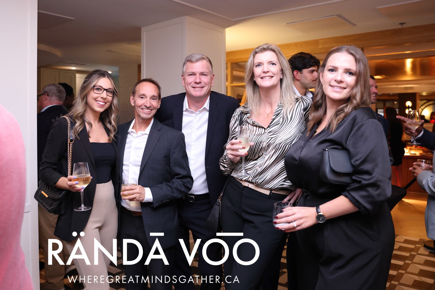 Five guests posing together with drinks at The Metcalfe Hotel reception.