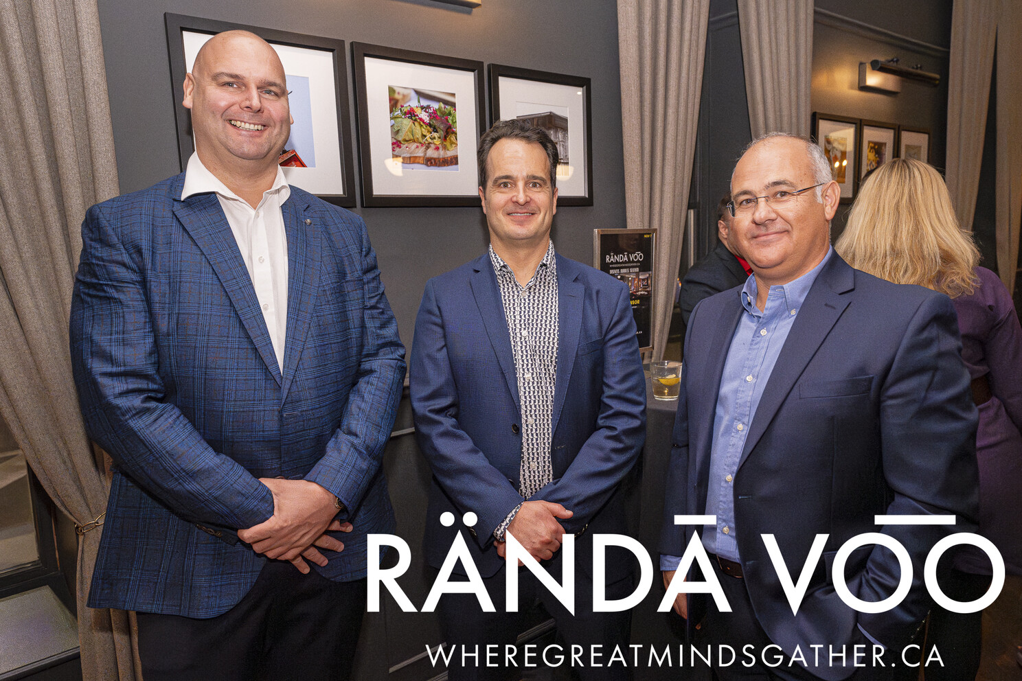 Three guests in blue jackets beside framed artwork at Business. Bubbles. Seafood.
