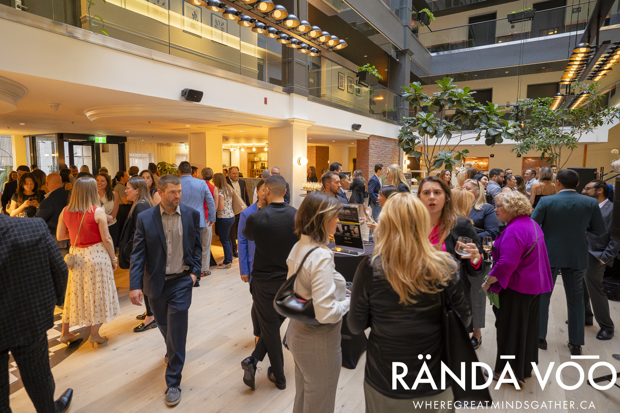Guests connecting throughout the sunlit atrium at The Metcalfe Hotel during a RÄNDĀ VO͞O gathering.