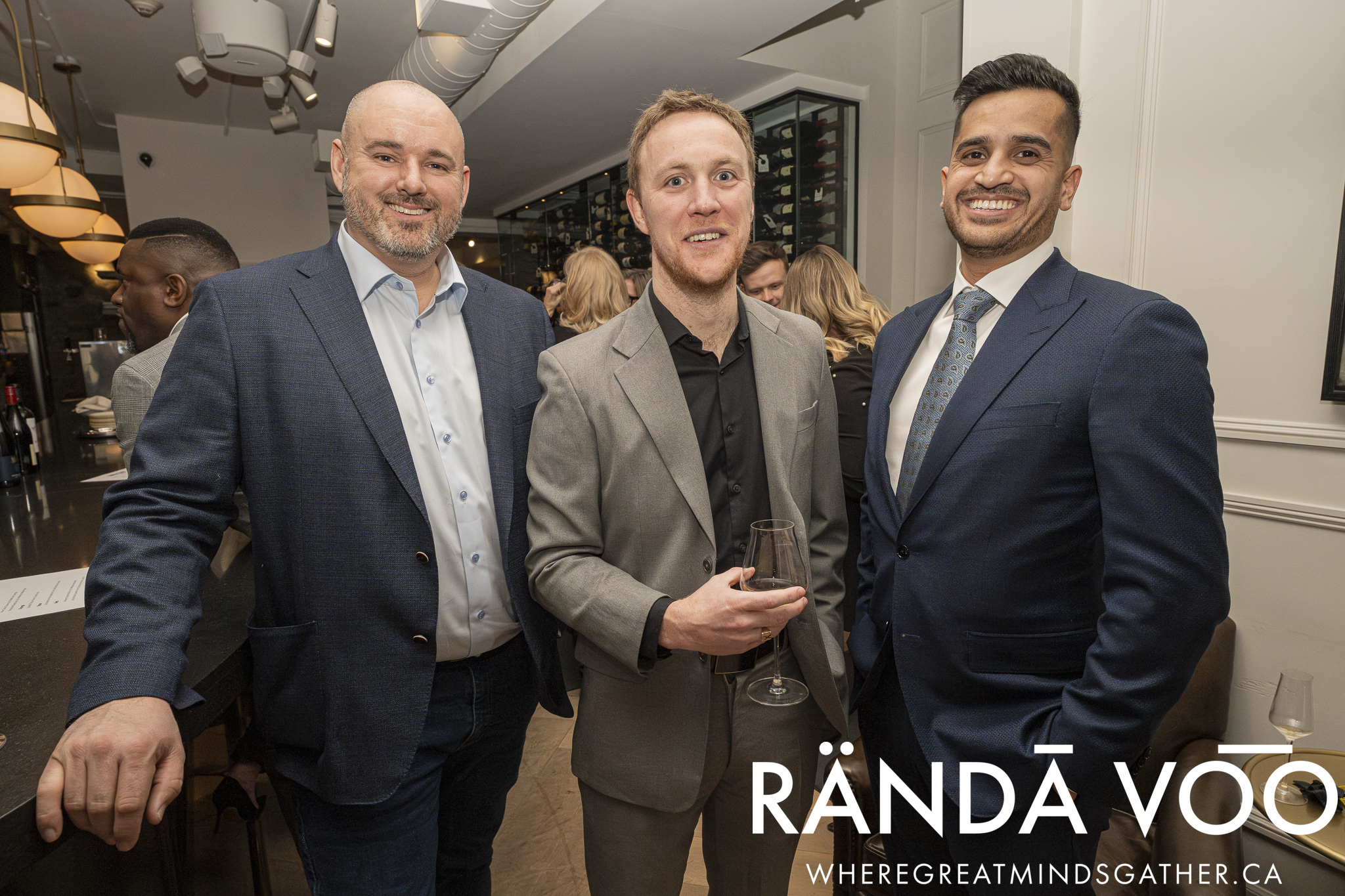 Three guests in suits smiling together at the Prestige gathering.