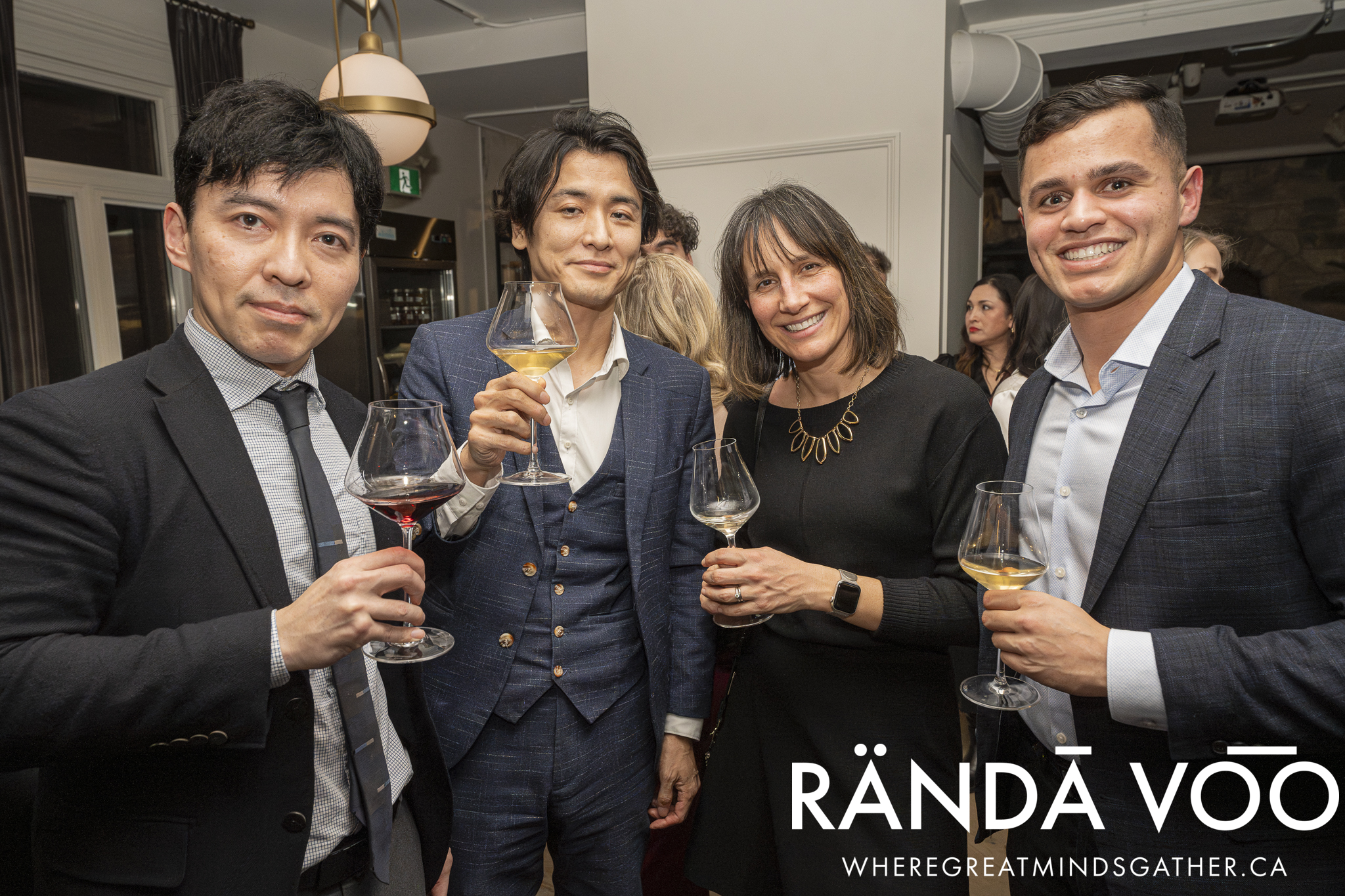 Four guests posing together with wine glasses at the Prestige gathering.