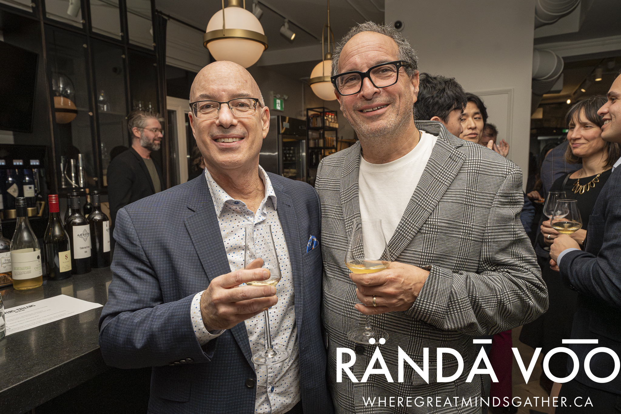 Two guests holding wine glasses beside the tasting counter.