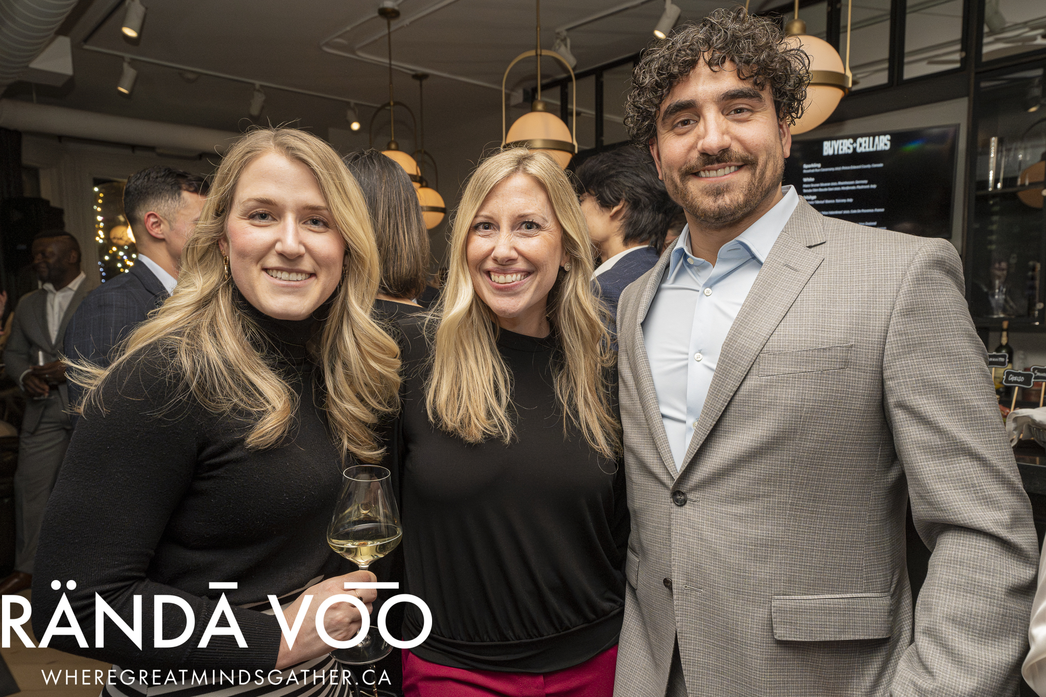 Three guests smiling together at the Prestige wine-tasting reception.