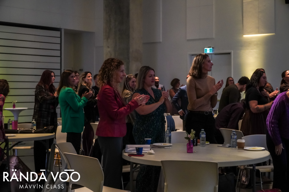 Guests standing and applauding around tables during MÄVVĪNCLASS The Capacity Room.