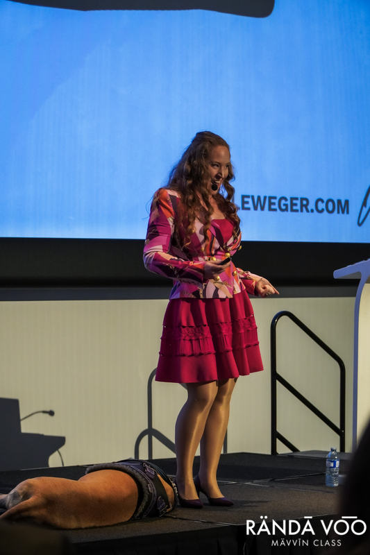 Michelle Weger speaking on stage with Quinn resting beside her at MÄVVĪNCLASS The Capacity Room.