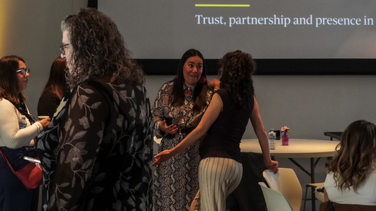 Guests standing and connecting around tables before the MÄVVĪNCLASS The Capacity Room program.