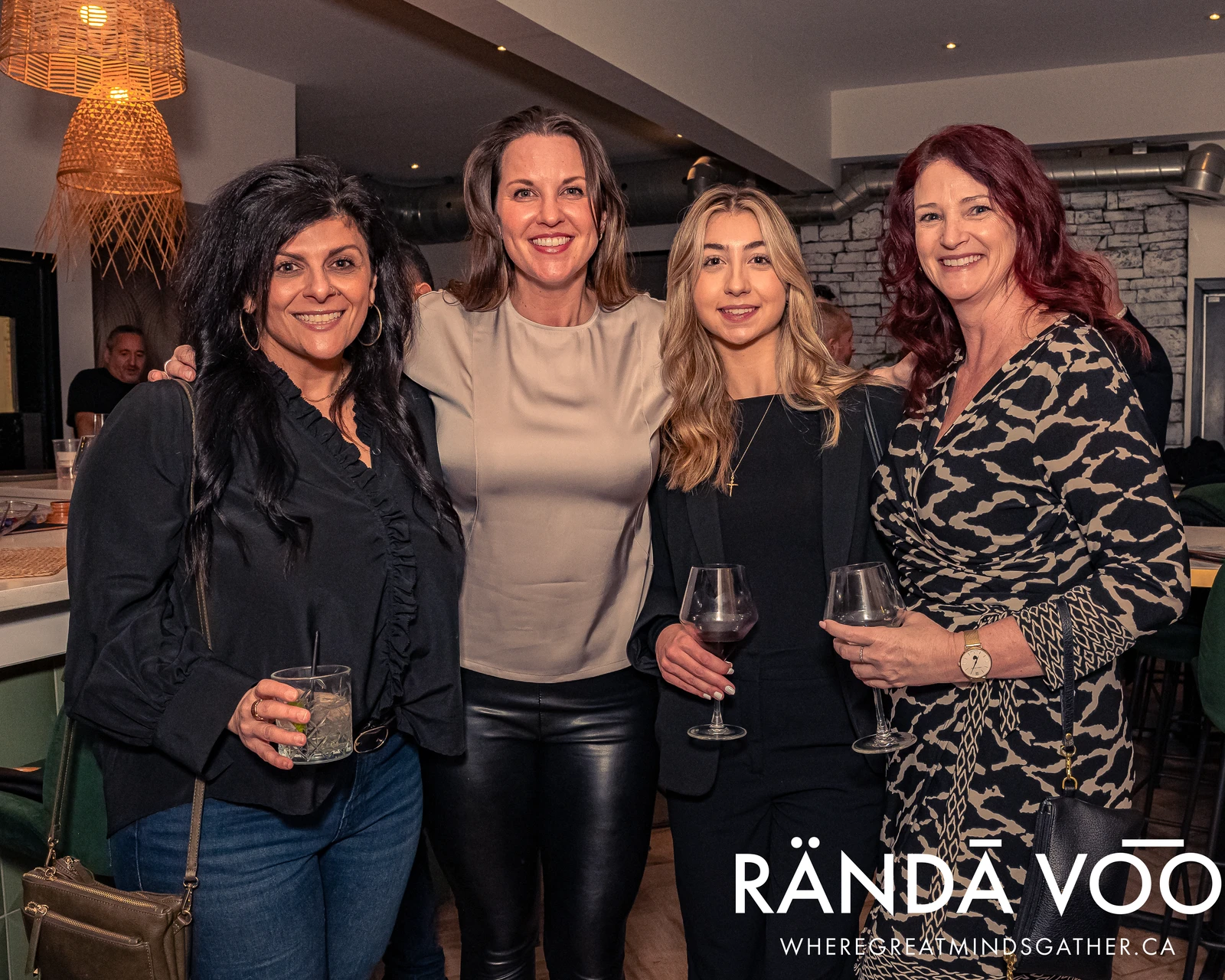 Four attendees posing together at a RÄNDĀ VO͞O business community evening gathering.