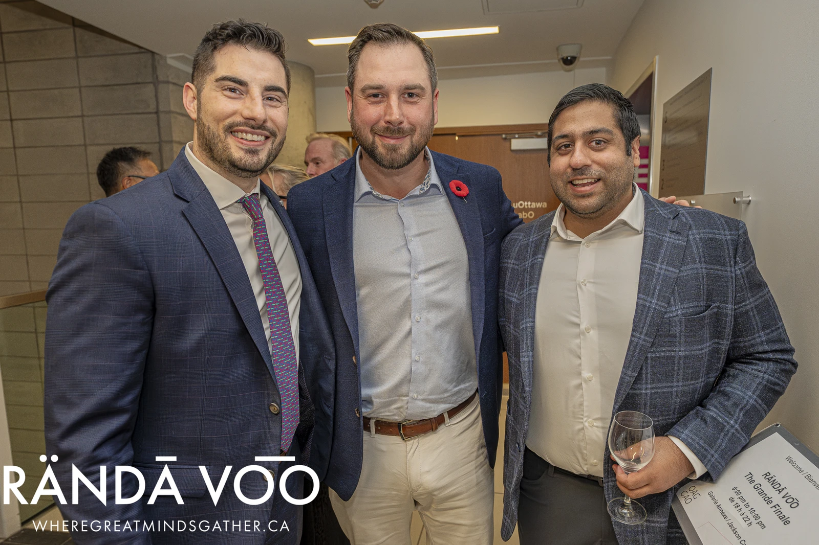 Three attendees in jackets posing together at a RÄNDĀ VO͞O business community event.
