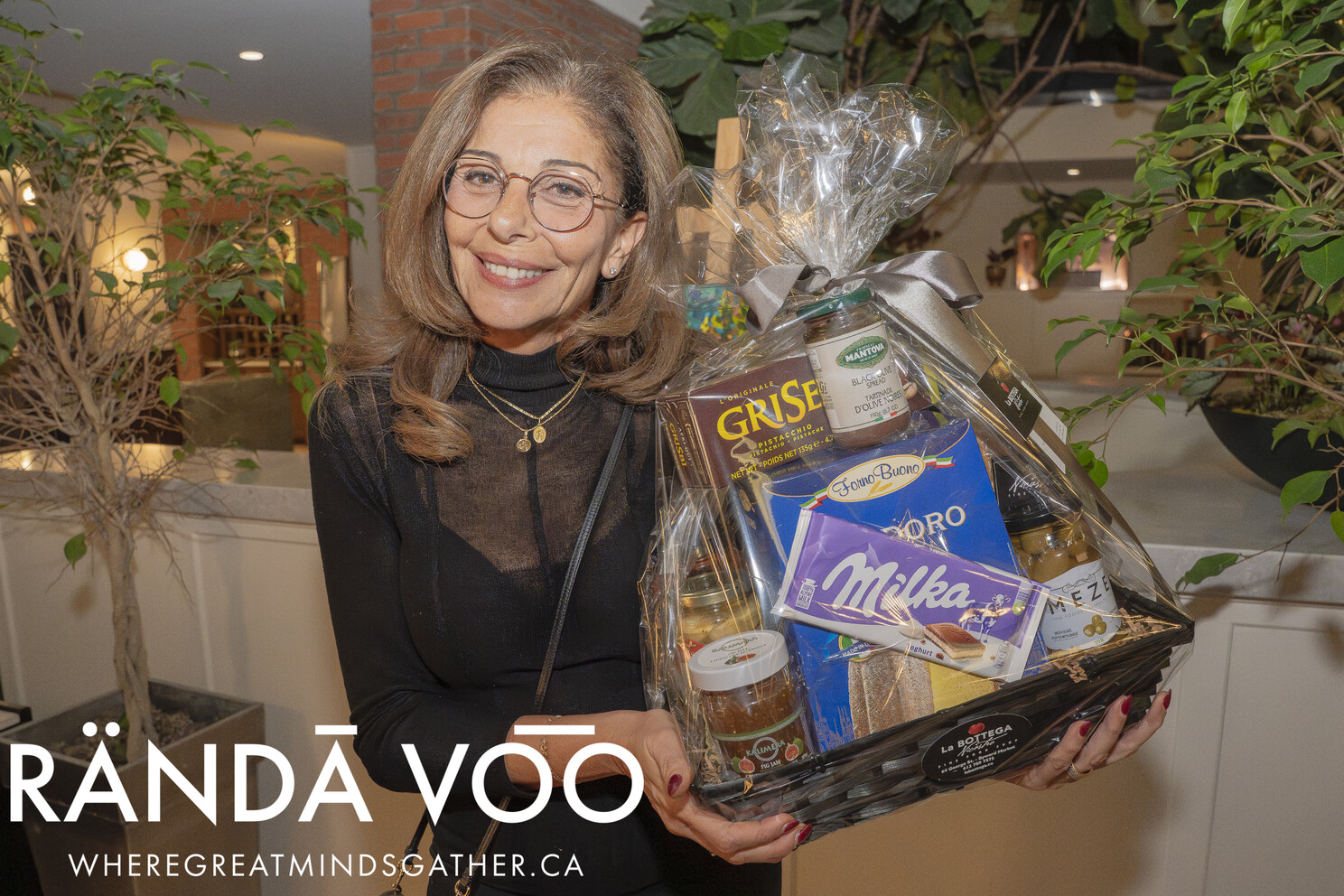A smiling guest holding a La Bottega gift basket at the grand finale.