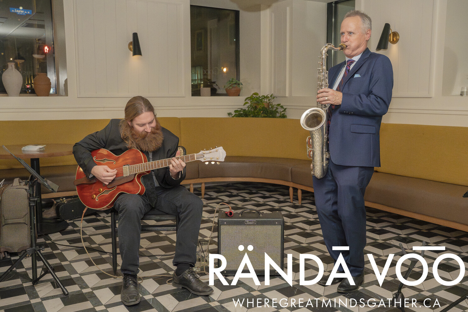 A guitarist and saxophonist performing together at the Tour Du RÄNDĀ VO͞O grand finale.
