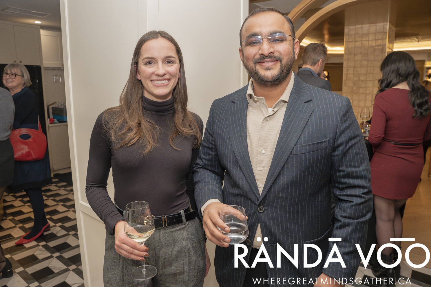 Two guests holding drinks and smiling at the grand finale reception.