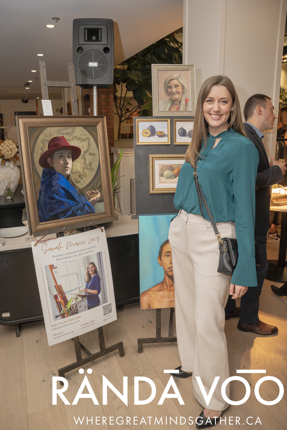 A guest standing beside a display of framed portrait paintings at the grand finale.