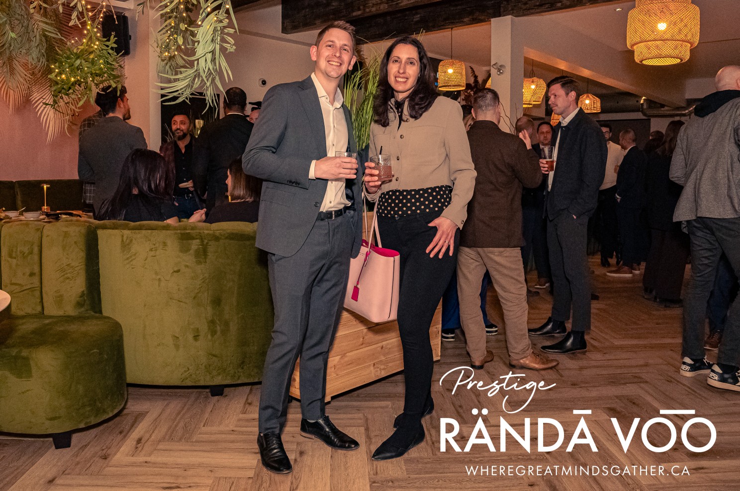 Two guests posing together beneath pendant lights at the Prestige reception.