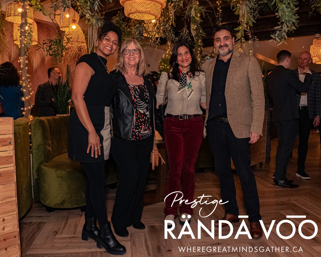 Four guests posing together beneath greenery at the Prestige reception.