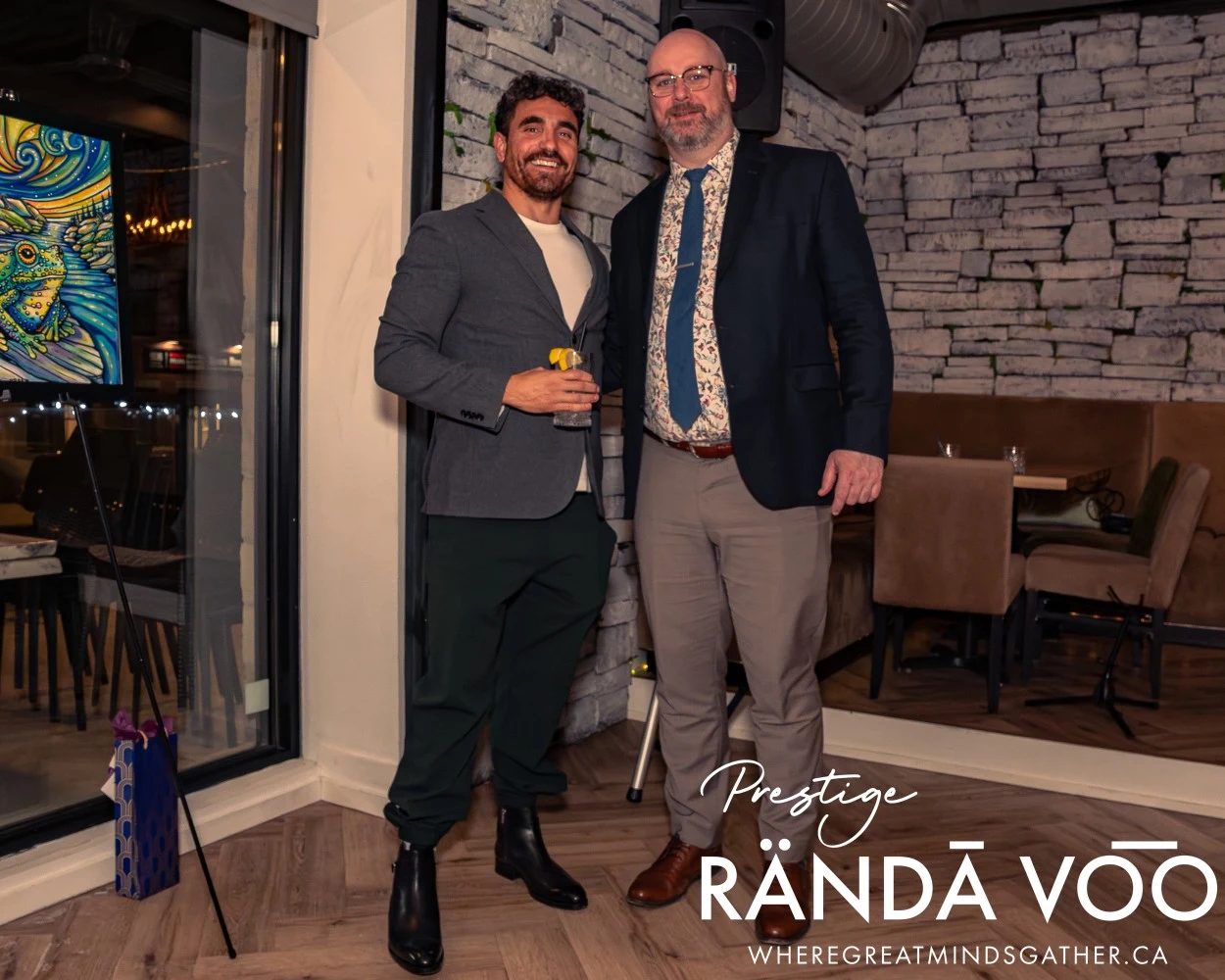 Two guests posing together at HEIST Manotick, with RÄNDĀ VO͞O Prestige branding.