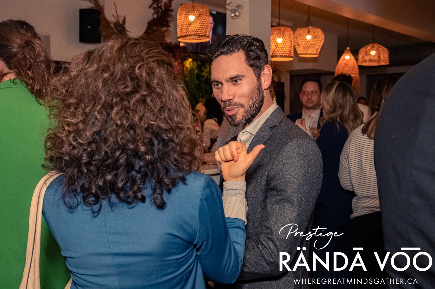 Guests sharing a conversation beneath pendant lights at the Prestige reception.