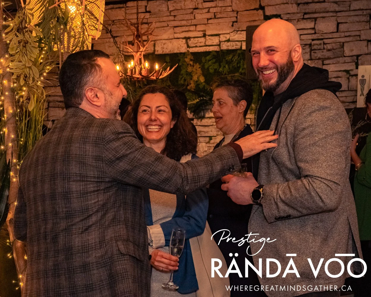 Guests smiling and chatting at HEIST Manotick, with RÄNDĀ VO͞O Prestige branding.