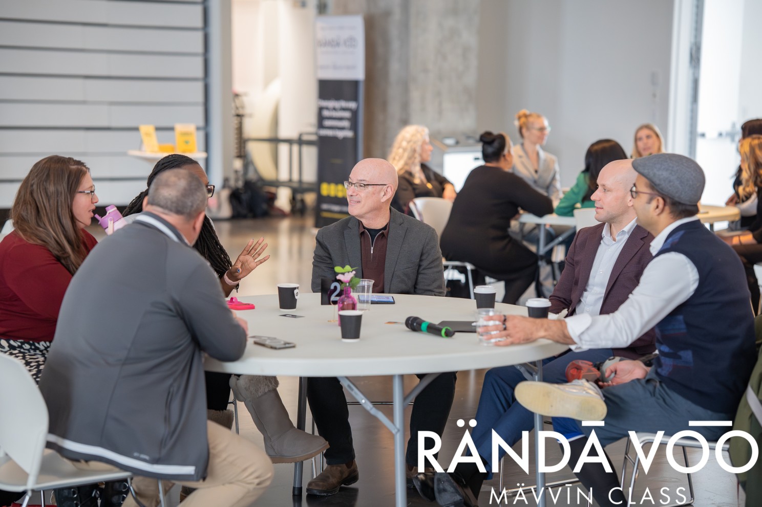MÄVVĪNCLASS participants in conversation around a round table.