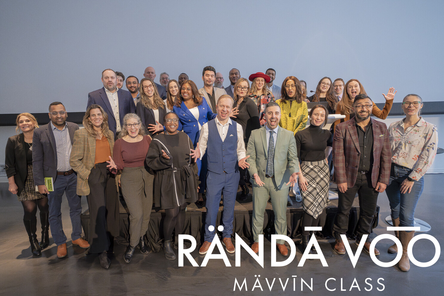 MÄVVĪNCLASS guests smiling together in front of a projection screen.