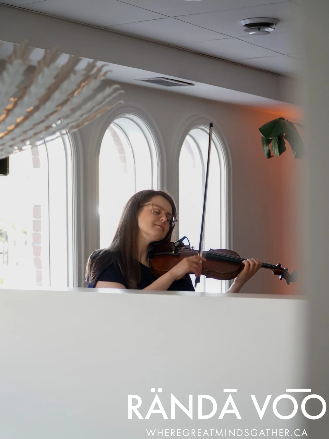 A violinist performing beside the arched windows at Parlour.